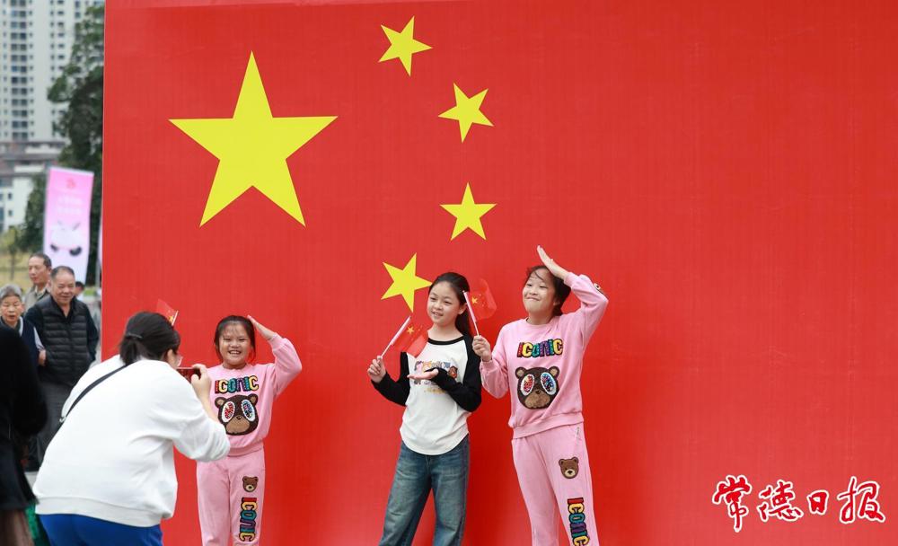 2024年10月1日，小游客们在新澳门葡京在线娱乐与国旗合影
