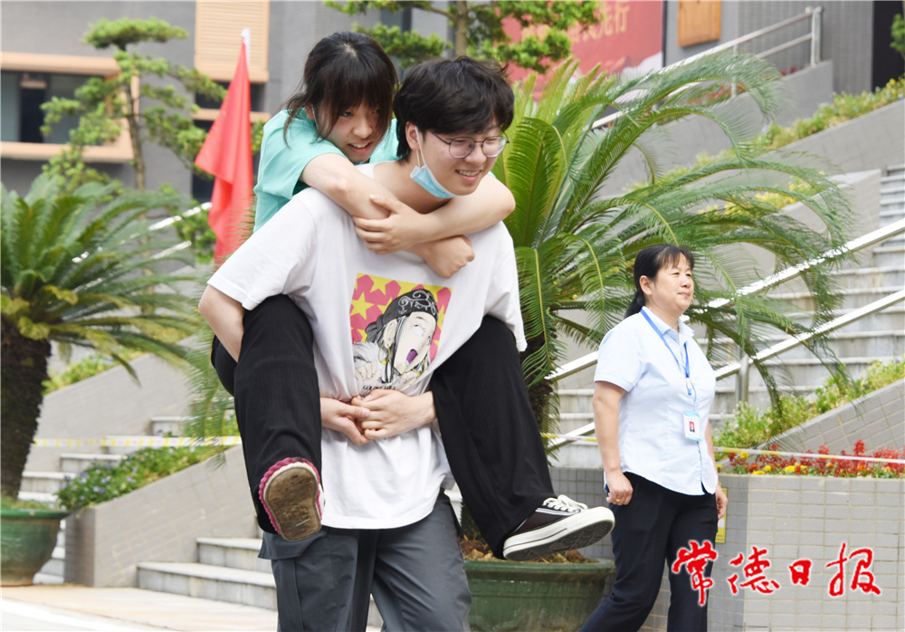 6月8日，普通高等学校招生全国统一考试湖南省澧县第二中学考点，一名男考生背着脚部受伤的女考生走向考场。 柏依朴 何祖华 摄.jpg